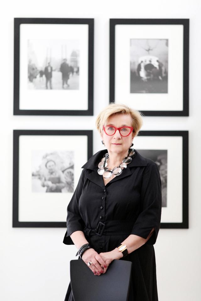 Hartigan standing in front of framed black and white photographs.
