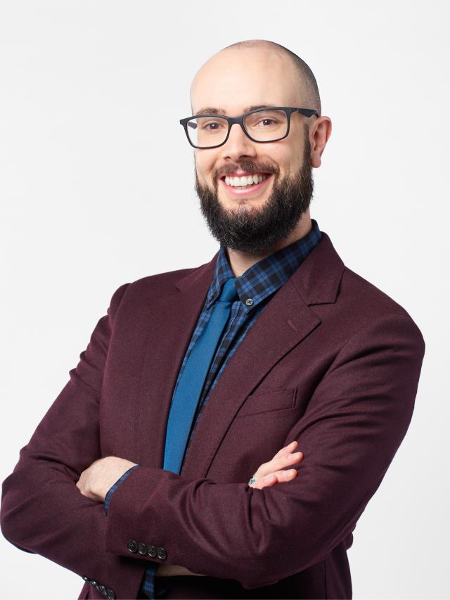 A man with a beard and glasses smiling at the camera.