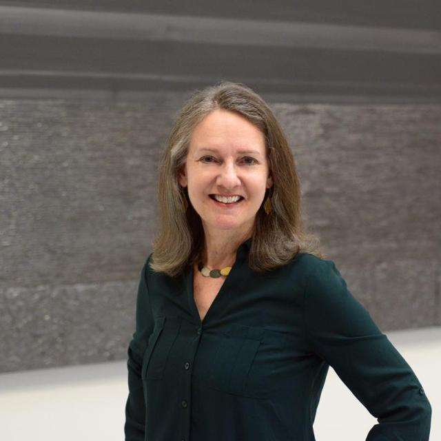 A woman standing in front of an artwork.