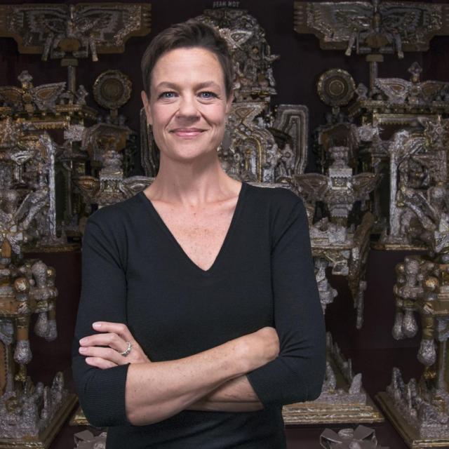 A photograph of a woman standing in front of artwork.