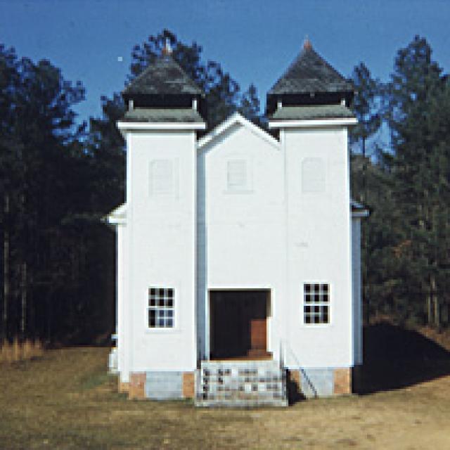 A painting of a white church in the woods
