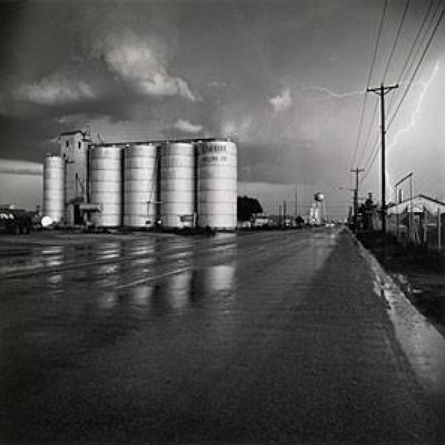 A photograph of a grain elevator in a lightning storm.