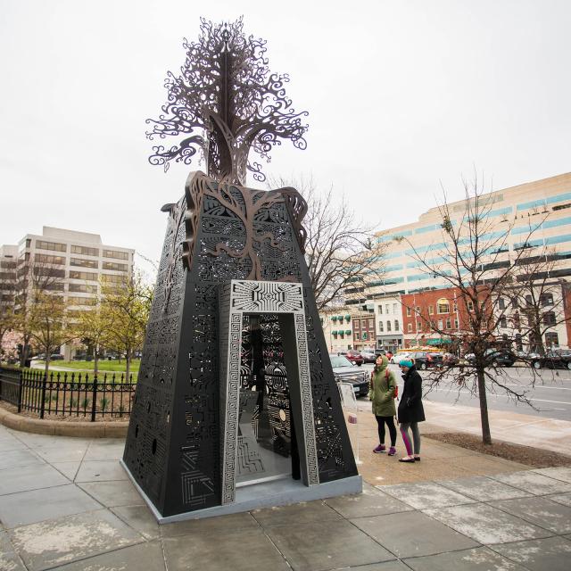 An image of a large scale installation of a small structure with a tree on top.