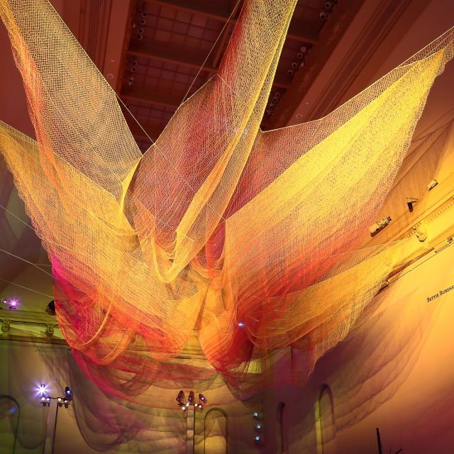 A photograph of colorful mesh hung from the ceiling inside the Grand Salon at the Renwick Gallery.