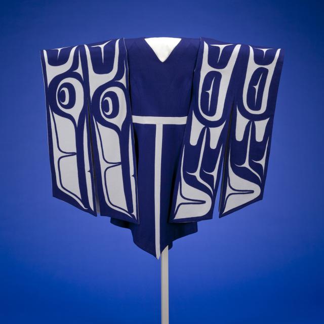 A blue dress handing on a stand with sleeves made of white and blue material depicting wings.
