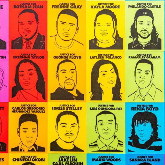 An installation photograph of an artwork of faces in a rainbow tone