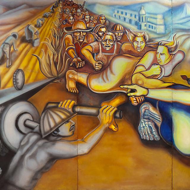 Detail of a mural showing an indigenous woman at the  forefront of a scene of farmworkers