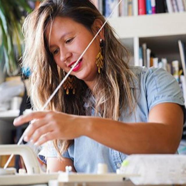 Maggie Thompson sits at a table making artwork