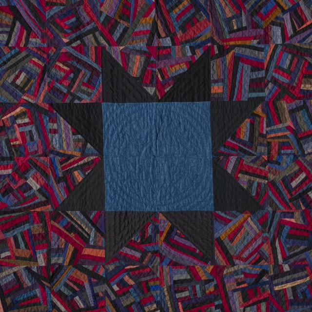 Quilt with a colorful, abstract pattern. At the center is a dark blue square with a black star as its border.