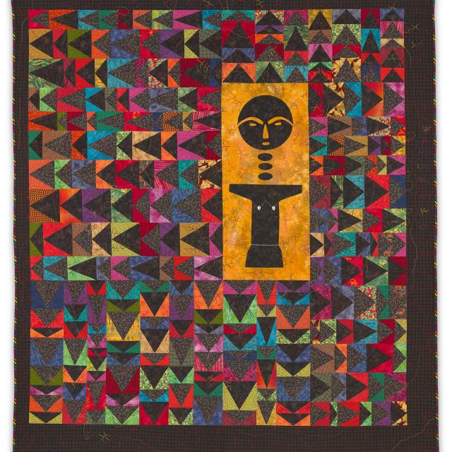 Patterned, multicolor quilt with a central Akuabaa figure.