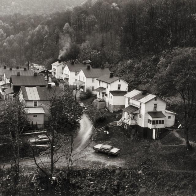 Black and white photograph of a row of houses seen from a distance.