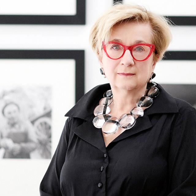Hartigan standing in front of framed black and white photographs.