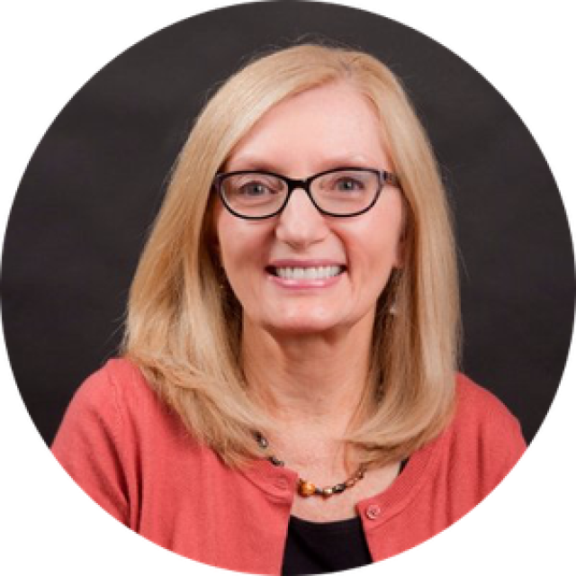 A photograph of a woman with blonde hair and glasses.